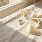 Bague en or blanc 9 carats sertie d'une perle blanche, posée sur un tissu lin.