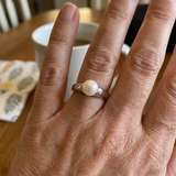 Bague en argent 925 ornée d'une perle de culture blanche portée à l'annulaire.