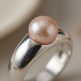 Gros plan sur la perle de culture rose sertie sur bague en argent 925.