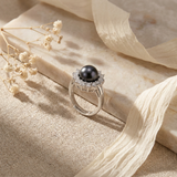 Bague en argent 925 ornée d'une perle noire entourée de zircons blancs.