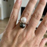Bague duo en or blanc 9 carats portée à la main, deux perles de culture blanche et noire Tahiti.