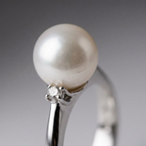 Gros plan sur la perle blanche et le diamant serti en or blanc 9 carats de la bague Alexandra.
