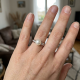 Bague en or blanc 9 carats avec perle de culture blanche et diamants, portée à l'annulaire.
