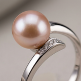 Gros plan sur bague or blanc 9 carats avec perle de culture rose et pavé de diamants.