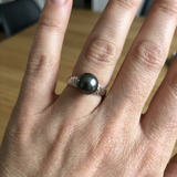 Bague en or blanc 9 carats sertie d'une perle de Tahiti noire portée à la main.