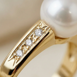 Gros plan sur le sertissage de trois diamants en or jaune 9 carats de la bague Ariane avec perle.