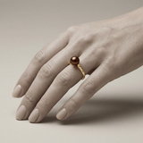 Bague or jaune 9 carats et perle de culture chocolat portée à l'annulaire.