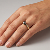 Bague or jaune 9 carats perle de Tahiti noire et diamants portée à l'annulaire.