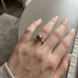 Bague en or jaune 9 carats portée à l'index, perle de Tahiti grise et diamants.