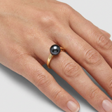 Bague en or jaune 9 carats sertie d'une perle de culture noire de Tahiti, portée à l'annulaire.