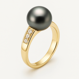 Bague or jaune 9 carats avec perle de Tahiti noire et diamants sur fond neutre.