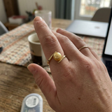 Bague zigzag en or jaune 9 carats avec perle de culture dorée, portée à l'index.