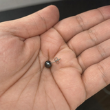 Boucle d'oreille bouton argent 925 et perle de culture noire de Tahiti posée dans une paume.