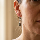 Boucles d'oreilles argent 925 en forme de cœur avec perle noire, portées à l'oreille.