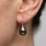 Boucles d'oreilles en or blanc 9 carats portées à l'oreille, avec perle de Tahiti noire en forme de goutte.