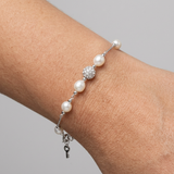 Bracelet en argent 925 avec perles de culture blanches et bille pavée de zircons au poignet.