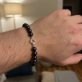 Bracelet en argent 925 et perles noires porté au poignet d'un homme.