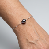 Bracelet or blanc 9 carats avec perle noire de Tahiti goutte, porté au poignet.
