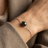 Bracelet en or blanc 9 carats avec une perle de Tahiti noire porté au poignet.
