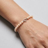 Bracelet en or blanc 9 carats et perles roses porté au poignet, fermoir anneau argent.