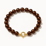 Bracelet en or jaune 9 carats et perles chocolat lustré sur fond neutre.