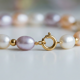 Gros plan sur le fermoir anneau en or jaune 9 carats du bracelet à perles de culture multicolores.
