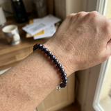 Bracelet en perles d'eau douce noires porté au poignet, fermoir en argent 925.