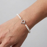 Bracelet perles blanches et argent 925 au poignet, fermoir anneau visible.