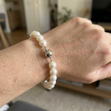 Bracelet perles blanches 8/9 mm et argent 925 avec fermoir boule, porté au poignet.