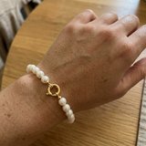 Bracelet en perles blanches et fermoir anneau or jaune 9 carats porté au poignet.