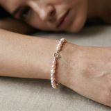 Bracelet en perles de culture multicolores avec fermoir en argent 925, porté au poignet.