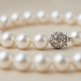 Gros plan sur le fermoir boule filigranée en argent 925 d'un bracelet en perles d'eau douce blanches.