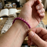 Bracelet perles d'eau douce rouge cerise en argent 925 porté au poignet, fermoir doré en main.