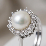 Bague argent 925 avec perle de culture blanche ronde entourée d'un halo de pierres blanches serties.