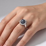 Bague en argent 925 avec perle noire entourée de zircons, portée à la main.