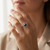 Bague en argent 925 avec perle noire entourée de zircons, portée à l'annulaire.