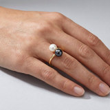 Bague duo or blanc 9 carats avec perle blanche et perle noire de Tahiti, portée à la main.
