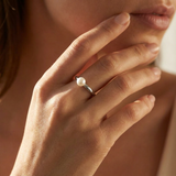 Bague jonc en argent 925 ornée d'une perle de culture blanche, portée à la main.