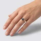 Bague or jaune 9 carats perle noire et diamants portée à l'annulaire.