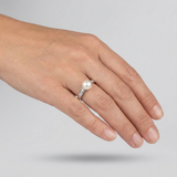 Bague en or blanc 9 carats ornée d'une perle de culture blanche et diamants, portée à l'annulaire.