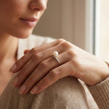 Bague en or blanc 9 carats avec perle de culture blanche et diamants portée à l'index.