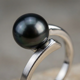 Gros plan sur la perle noire de Tahiti d'une bague en or blanc 9 carats au design torsadé.