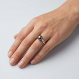 Bague or blanc 9 carats et perle de Tahiti noire portée à l'index d'une main féminine.