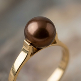 Gros plan sur la perle chocolat ronde d'une bague en or jaune 9 carats.