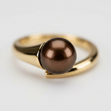 Bague or jaune 9 carats tenant une perle de culture chocolat ronde en serti bypass.
