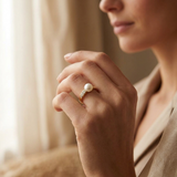 Bague en or jaune 9 carats avec perle de culture blanche et diamants portée à la main.