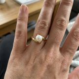 Bague or jaune 9 carats et perle de culture blanche portée à l'annulaire, monture croisée.