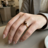 Bague en or jaune 9 carats ornée d'une perle de culture chocolat, portée à l'index.