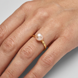 Bague en or jaune 9 carats sertie d'une perle de culture rose, portée à l'index.