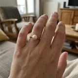 Bague en or jaune 9 carats ornée d'une perle de culture rose portée à la main.